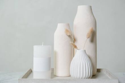A candle beside white vases